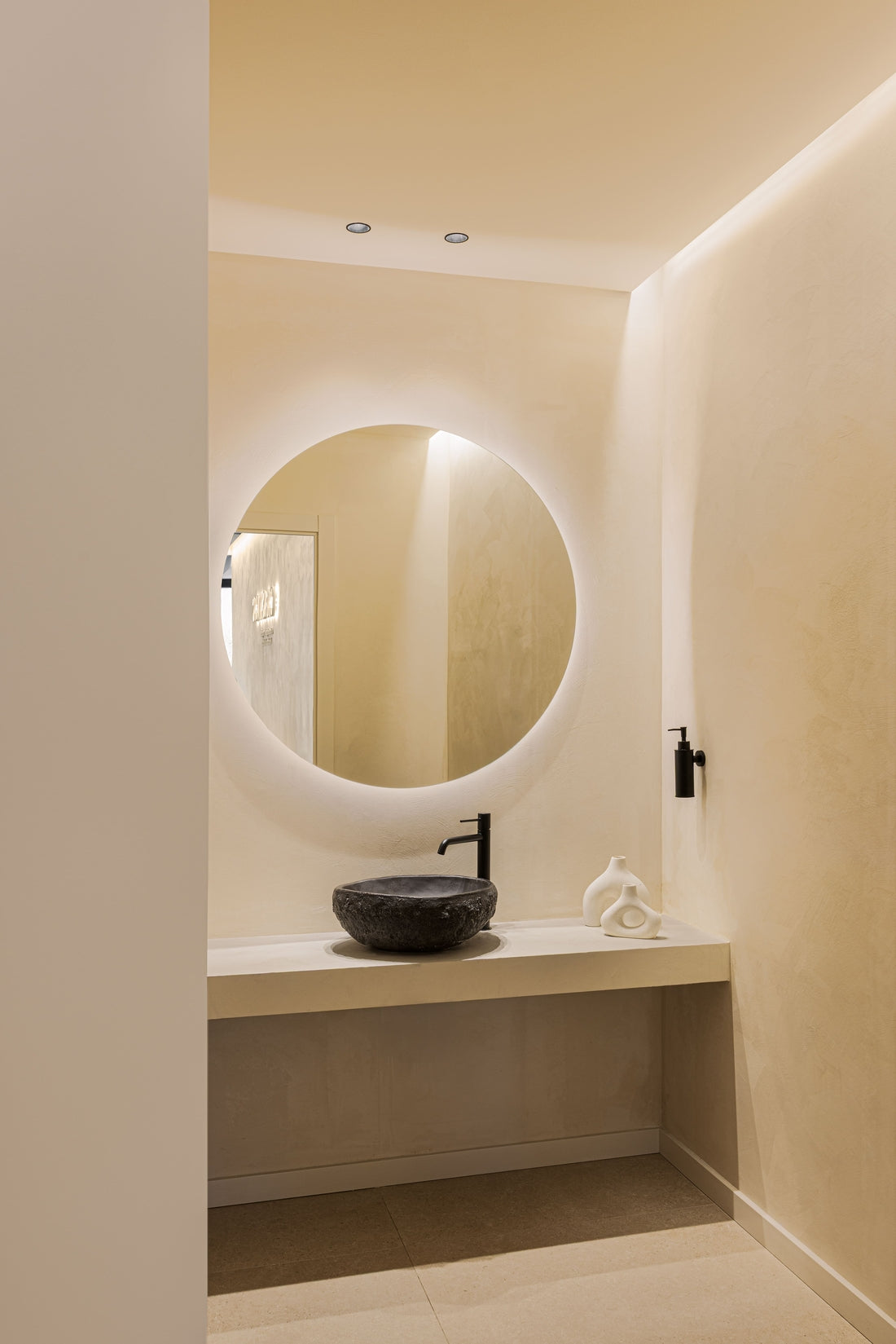 Focos empotrables Tolva S de Nexia sobre un lavabo con espejo circular en un baño de tonos cálidos.